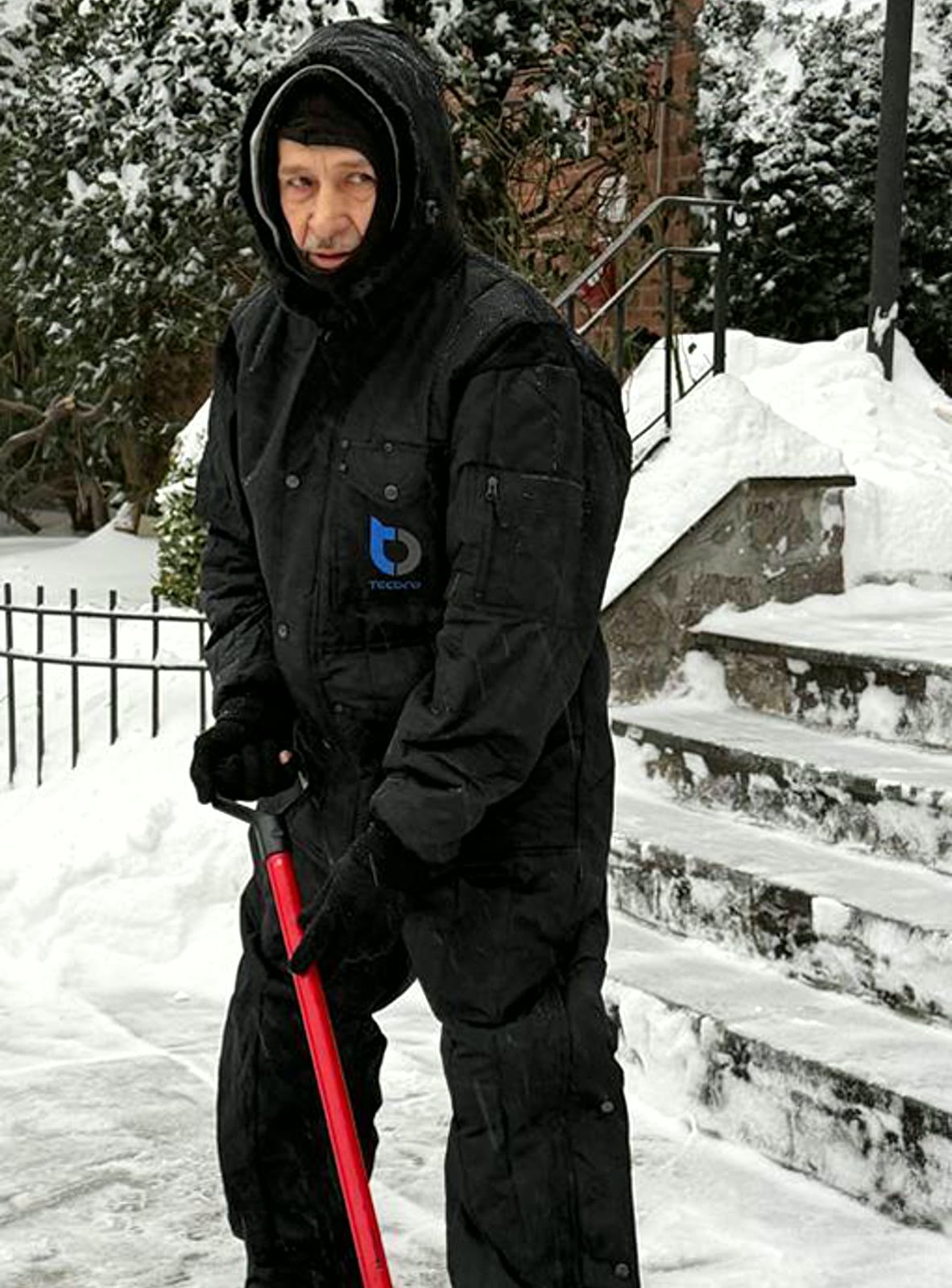 Tecbro worker pulling pallet jack in snow wearing insulated coveralls